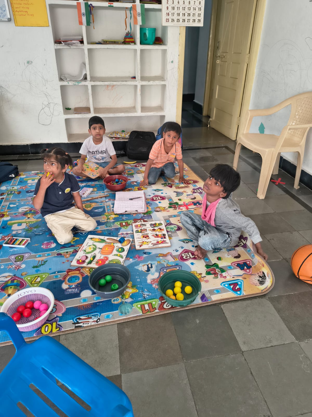 Children at the special school working with learning materials and puzzles on a play mat